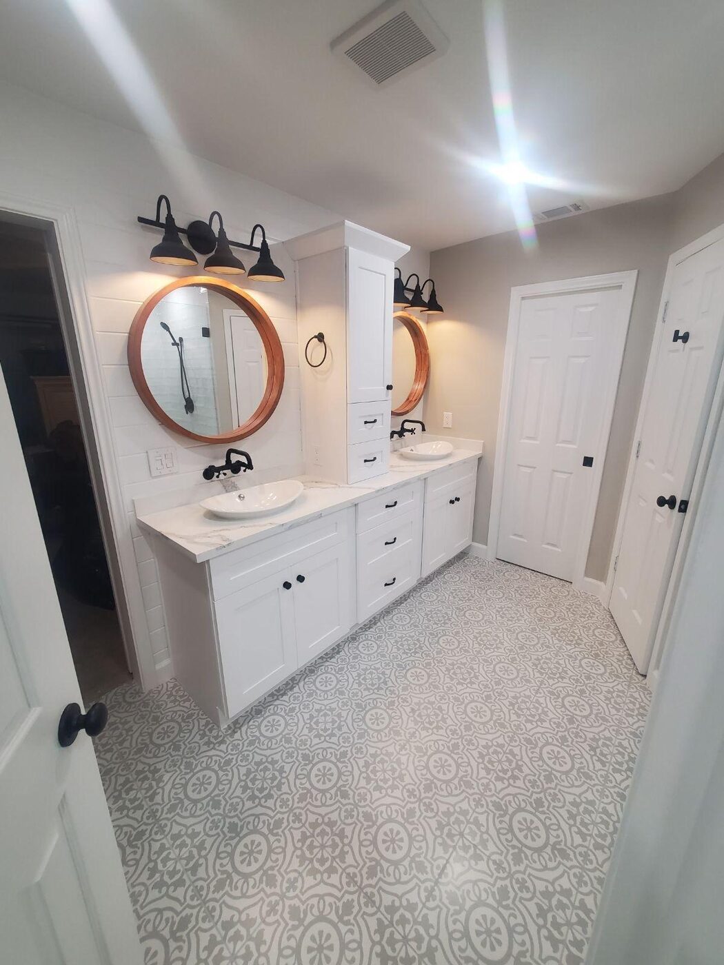 Double vanity with round mirrors and patterned tile floor