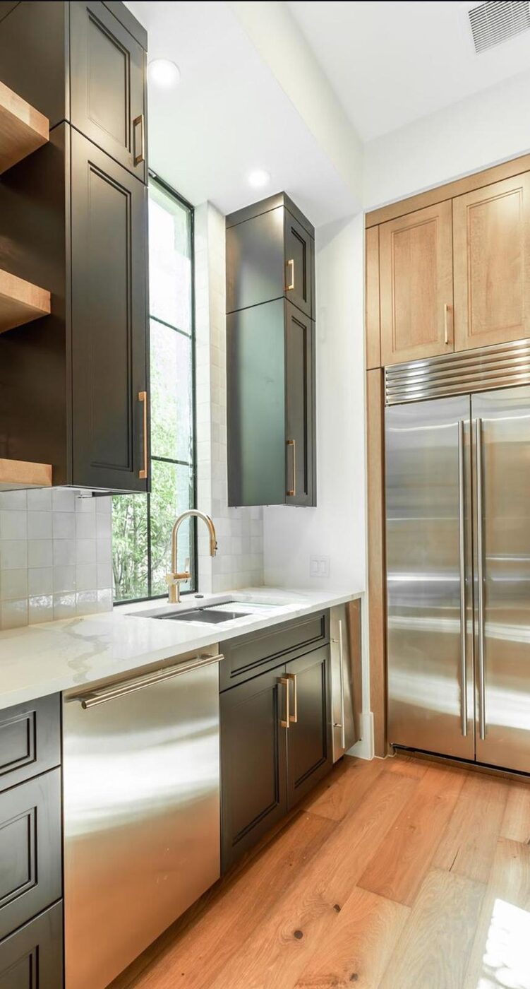 Charcoal cabinetry with brass hardware and open oak shelving